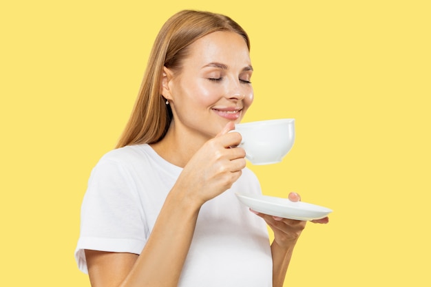 Portrait de demi-longueur de jeune femme caucasienne sur studio jaune