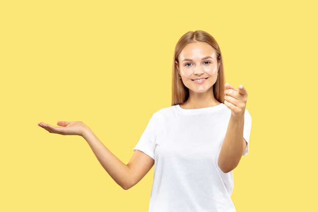 Portrait de demi-longueur de jeune femme caucasienne sur studio jaune