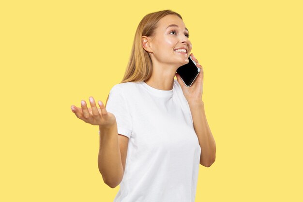 Portrait de demi-longueur de jeune femme caucasienne sur studio jaune