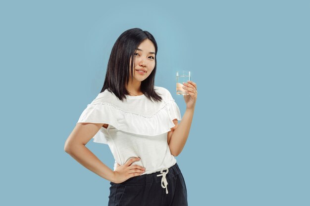 Portrait demi-longueur de la jeune femme coréenne sur fond bleu