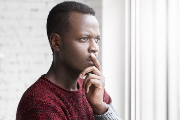 Portrait de demi-profil de beau jeune écrivain afro-américain à la recherche d'une fenêtre