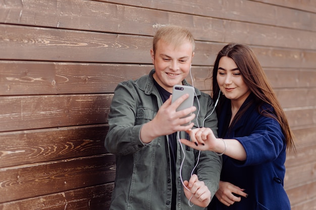 Portrait de deux amis à l'aide de téléphone portable et d'écouter de la musique dans la rue