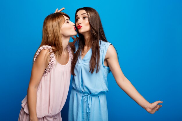 Portrait de deux belles filles sur mur bleu