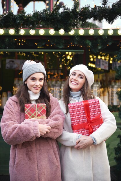 Portrait de deux femmes avec des cadeaux sur le marché de Noël