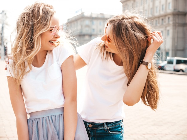 Photo gratuite portrait de deux jeunes belles filles blondes souriantes hipster dans des vêtements de t-shirt blanc à la mode d'été.