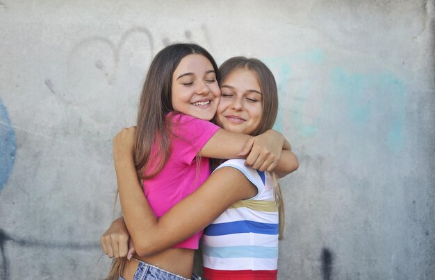 portrait de deux jeunes filles embrassées appuyées contre un mur avec des graffitis