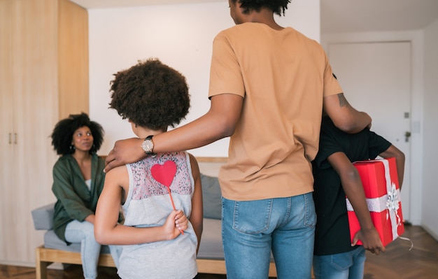 Portrait de deux petits garçons cachant un cadeau pour maman derrière le dos à la maison. Concept de célébration de la fête des mères.