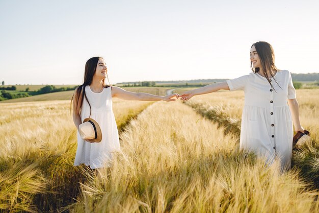 Portrait de deux sœurs en robes blanches aux cheveux longs dans un champ