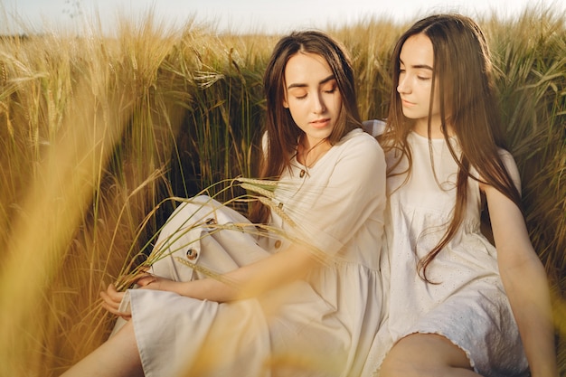 Portrait de deux sœurs en robes blanches aux cheveux longs dans un champ