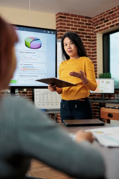 Portrait d'un directeur exécutif tenant un presse-papiers expliquant les statistiques marketing discutant de la stratégie pour augmenter les revenus lors d'une réunion d'affaires au bureau de démarrage. Femmes d'affaires travaillant au projet d'entreprise