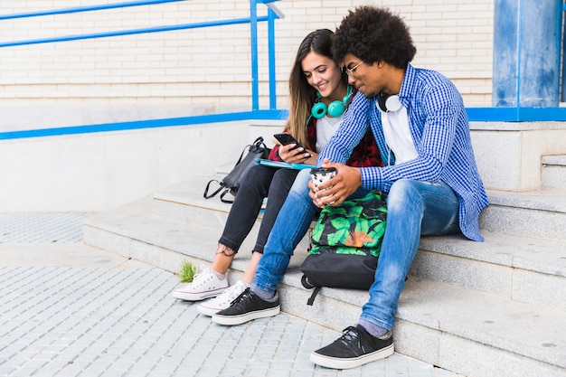 Portrait de divers adolescents et étudiantes assis sur les marches à l&#39;aide d&#39;un téléphone portable