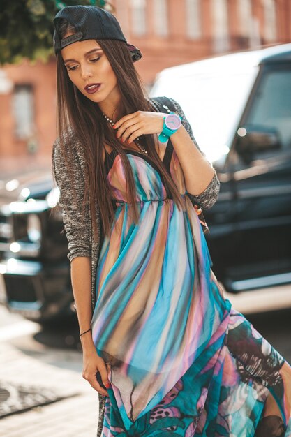 Portrait du beau modèle d'adolescent brune glamour dans des vêtements et un sac hipster d'été. Fille posant dans la rue. Femme, casquette