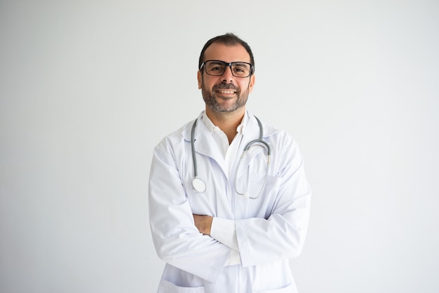 Portrait du docteur adulte moyen réussi avec les bras croisés.