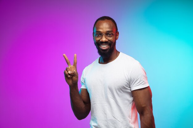 Portrait du jeune homme afro-américain sur studio dégradé en néon