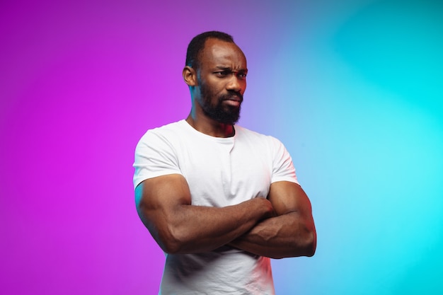 Portrait du jeune homme afro-américain sur studio dégradé en néon