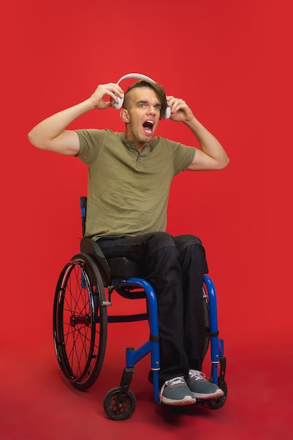 Portrait du jeune homme caucasien sur studio rouge. Concept d'émotions humaines