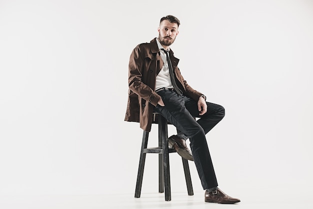 Portrait d'élégant beau jeune homme assis contre le blanc. Homme, porter, veste