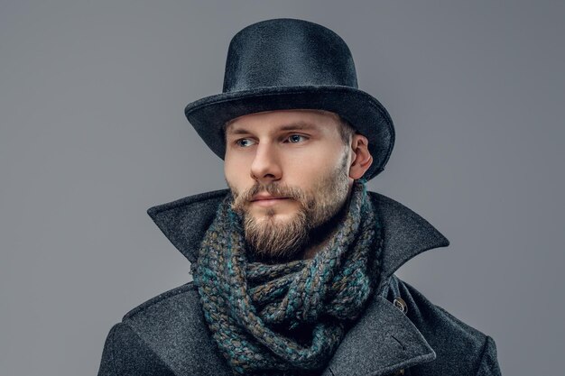 Portrait d'un élégant hipster barbu vêtu d'une veste élégante et d'un chapeau cylindrique.