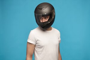 Photo gratuite portrait d'élégant jeune homme portant un t-shirt blanc et un casque de moto posant