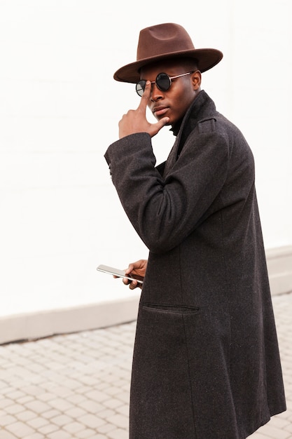 Portrait de l'élégant mâle adulte posant avec des lunettes de soleil