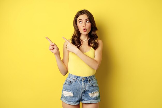 Portrait d'élégante fille d'été femme brune montrant le chemin pointant du doigt la gauche de la publicité standin...