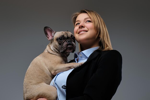 Portrait d'un éleveur de femme blonde heureuse tient son mignon carlin. Isolé sur un fond gris.