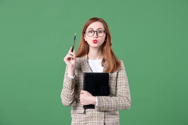 Portrait d'enseignante en costume avec bloc-notes et stylo sur vert