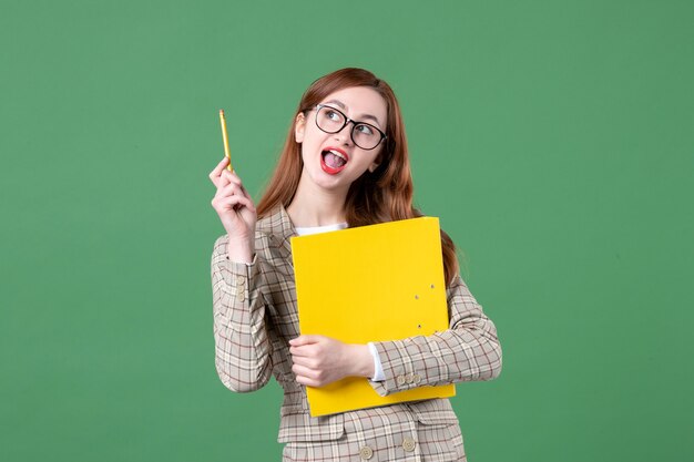 Portrait d'enseignante tenant des fichiers jaunes sur vert