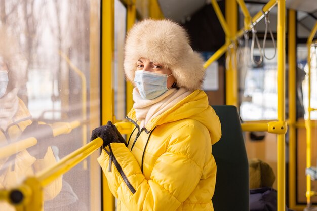 Portrait ensoleillé lumineux d'une jeune femme en vêtements chauds dans un bus de la ville un jour d'hiver
