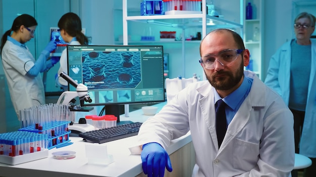 Portrait épuisé d'un médecin chimiste regardant une caméra vidéo assis dans un laboratoire équipé travaillant tard dans la nuit