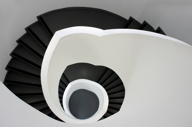 Portrait d'un escalier noir descendant entouré de murs blancs
