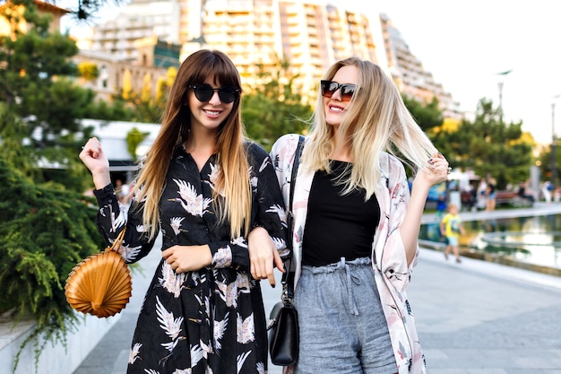 Portrait d'été de deux élégantes meilleures amies femme ayant du bon temps ensemble, souriant et passer du temps dans la rue, des vêtements à la mode élégants et des lunettes de soleil, un couple heureux, des relations.