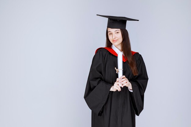 Portrait d'étudiant diplômé en robe montrant un certificat collégial. photo de haute qualité