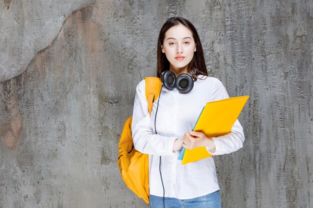 Portrait d'étudiant avec sac à dos jaune et livres posant. Photo de haute qualité