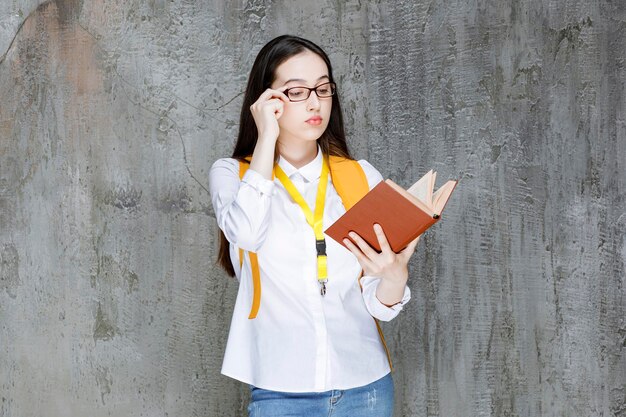 Portrait d'une étudiante à lunettes lisant un livre. Photo de haute qualité