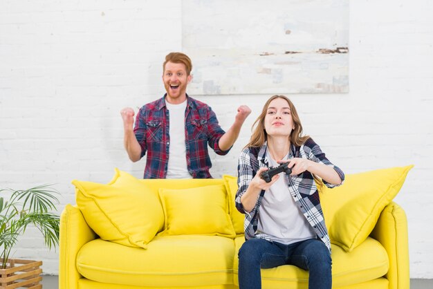 Portrait, excité, jeune, homme, debout, derrière, femme, jeu vidéo, chez soi