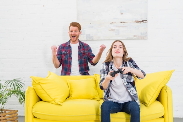 Portrait, excité, jeune, homme, debout, derrière, femme, jeu vidéo, chez soi