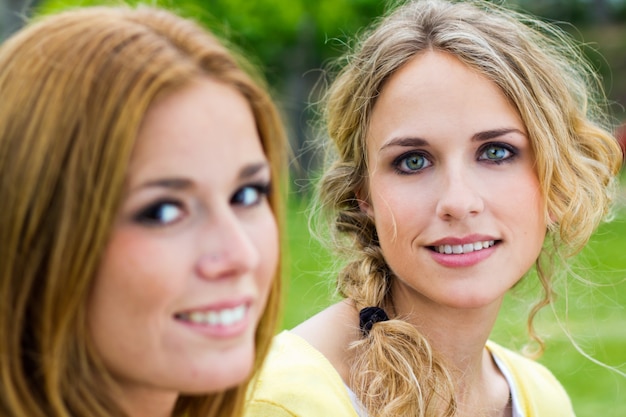 Portrait extérieur de deux belles jeunes femmes posant au parc