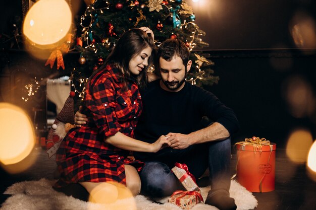 Portrait de famille. Charmant couple de femme enceinte en chemise à carreaux et bel homme pose dans un confortable