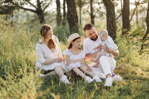 Portrait de famille heureuse au coucher du soleil, passer du temps et jouer dans la nature.