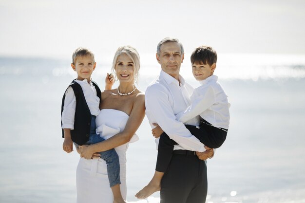 Portrait de famille heureuse sur la journée ensoleillée avec deux fils adolescents qui sont assis sur les mains des parents