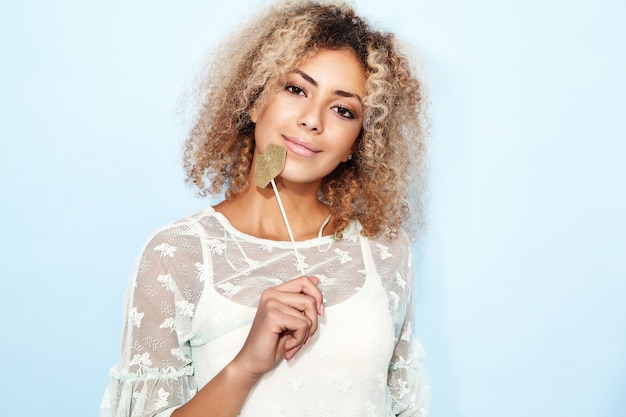 Portrait d'une femme adorable et heureuse avec une coiffure africaine blonde avec de grosses lèvres sur un bâton.