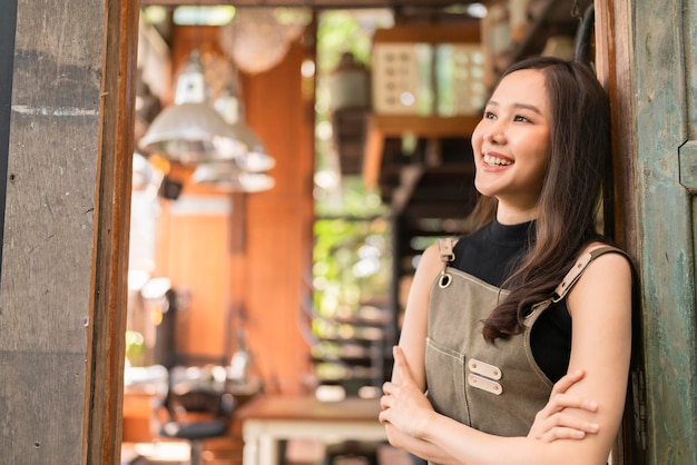 Portrait d'une femme adulte asiatique portant un tablier debout à l'entrée de son atelier de poterie tissu décontracté se détendre souriant confiant et chaleureux femme asiatique avec son atelier de studio à domicile