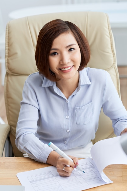 Portrait de femme d'affaires asiatiques assis dans la chaise de bureau, prenant des notes dans les papiers