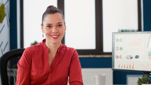 Portrait d'une femme d'affaires confiante avec un poste de direction travaillant avec des statistiques de gestion et de marketing sur ordinateur. Employé de bureau analysant des graphiques de recherche et des rapports de données.