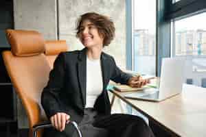 Photo gratuite portrait d'une femme d'affaires parlant à un collègue dans un bureau assis avec un ordinateur portable et