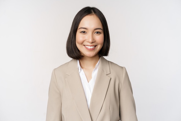 Portrait d'une femme d'affaires prospère en costume souriant et ressemblant à un professionnel sur fond blanc de caméra