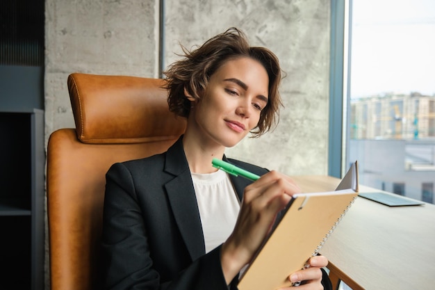 Photo gratuite portrait d'une femme d'affaires prospère signant des contrats en lisant des documents dans son bureau