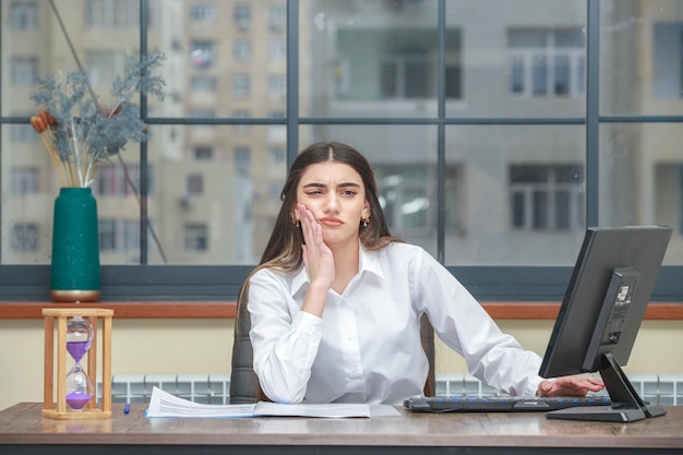 Portrait d'une femme d'affaires réfléchie assise au bureau et pensant