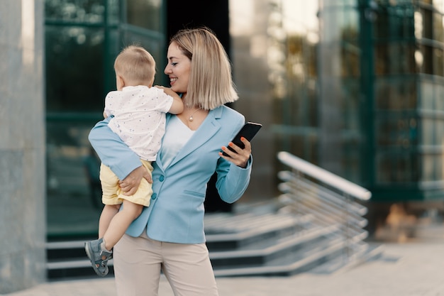 Portrait d'une femme d'affaires réussie en costume bleu avec bébé